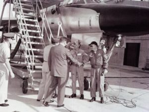 Historic photo of a B-58 flight crew shaking hands with a man in a suit outside of their plane.