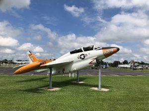 Side view of the T-2A Naval plane mounted on three steel beams and painted in its orange color scheme on nose, wings, and tail.