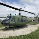 Side view of an army green Huey helicopter.