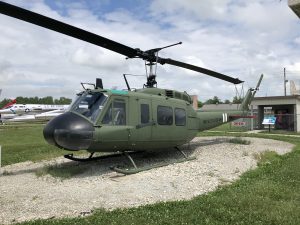 Side view of an army green Huey helicopter.