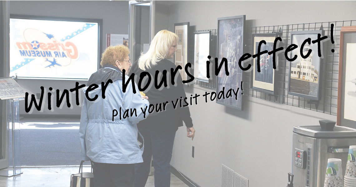 Guests looking at some pictures on the wall with the words "Winter Hours in effect! Plan your visit today!"