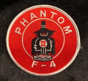 Red circle shaped patch with white trim and lettering saying Phantom F-4 with a black, red, and white colored Spooky