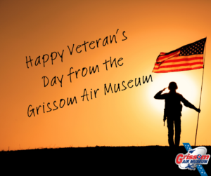Silhouette of a solider standing with a clearly seen American flag against a sunset overlaid with the words "Happy Veteran's Day from the Grissom Air Museum"